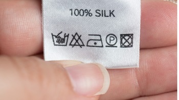hand houdt kledinglabel met symbolen voor wassen, drogen en strijken vast